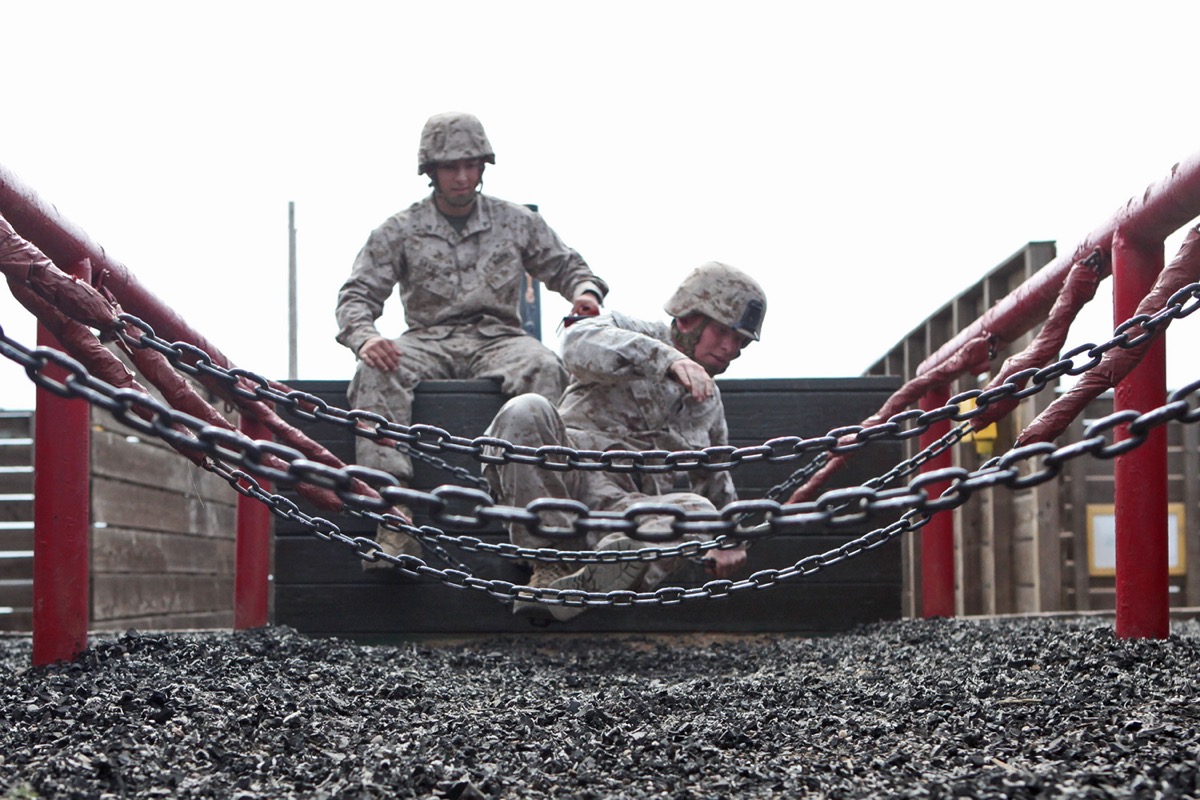 A U.S. Marine helping another Marine across a chain bridge obstacle on the leadership reaction course at Camp Pendleton